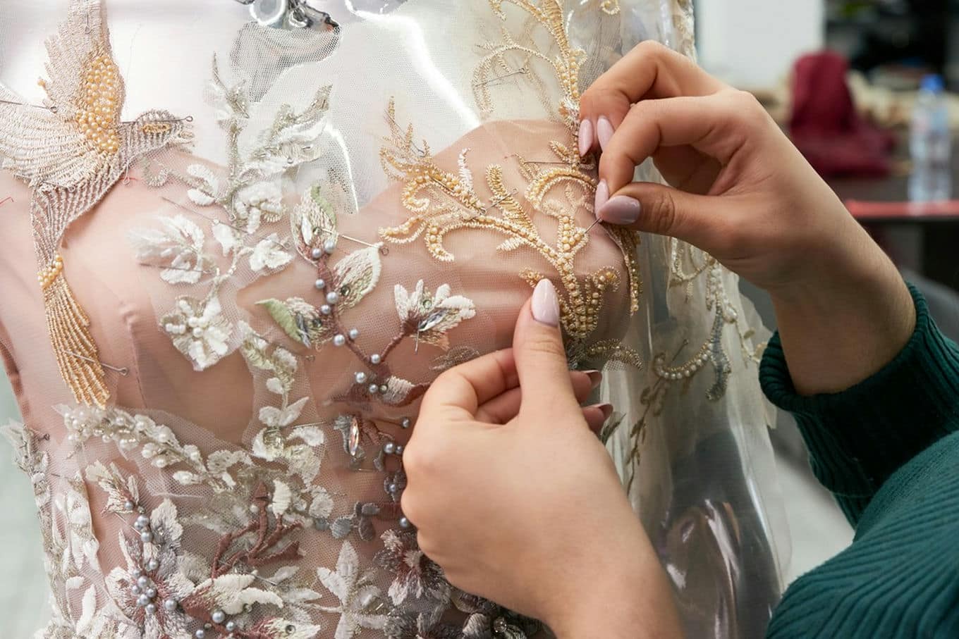 krawcowa przyszywa ornamenty na sukni