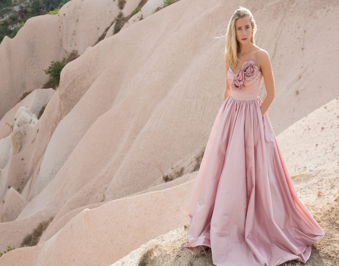 młoda kobieta pozuje na pustyni w różowej sukience